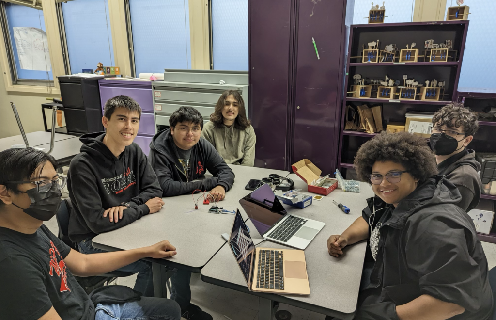 Members of the CubeSat club pose with computers and equipment during a lunch meeting.